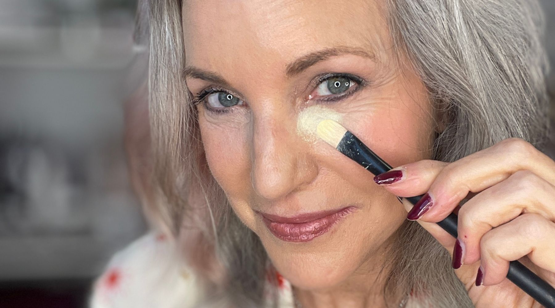 applying yellow color corrector with makeup brush to cover blue purple dark circles