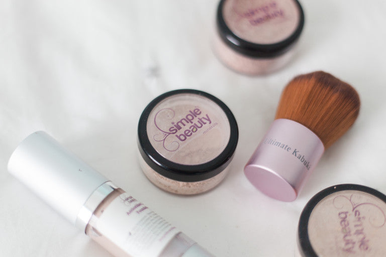 foundation bottle, powder foundation jars and a pink kabuki brush