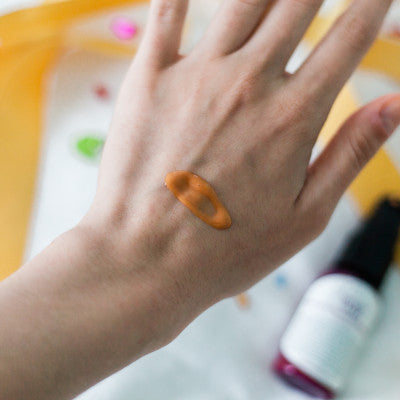 serum on woman's hand with serum bottle in the background