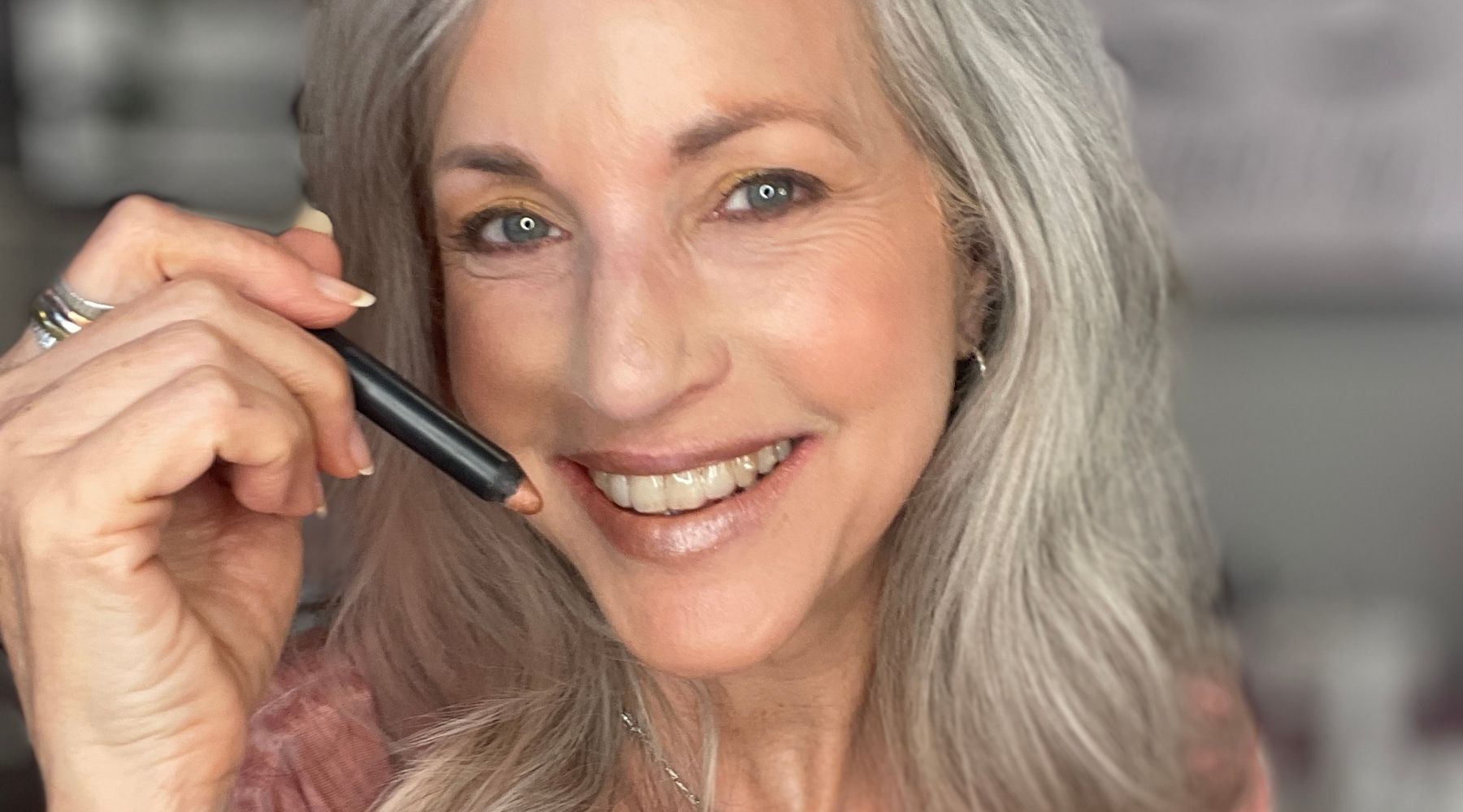 woman smiling holding makeup stick.