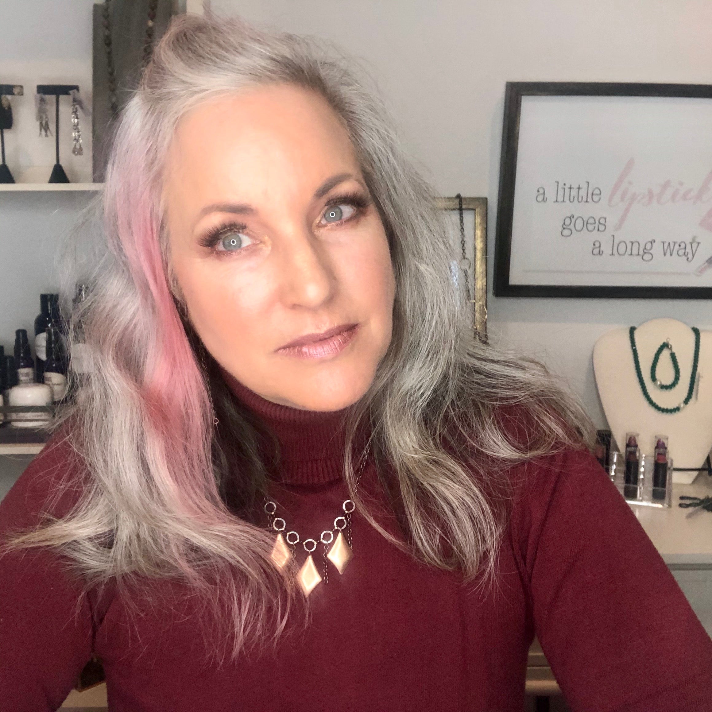 lisa with burgundy sweater on and copper necklace, and pink hair.