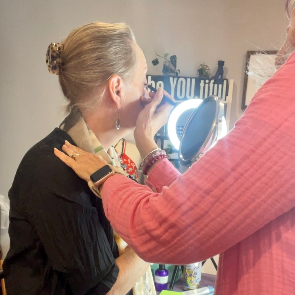 makeup artist applying eye brow makeup to client.