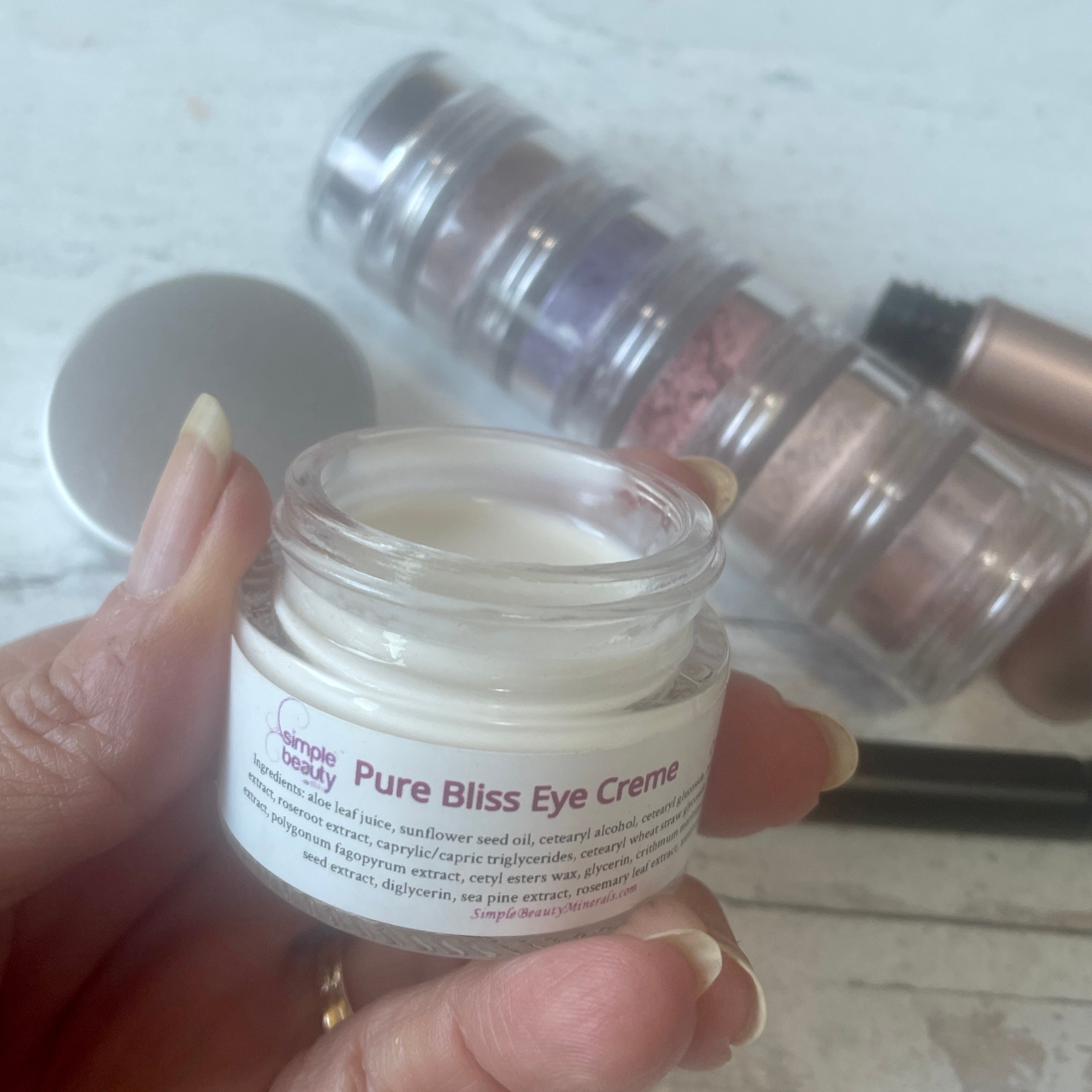 open jar of eye creme in hand with eyeshadow stacker