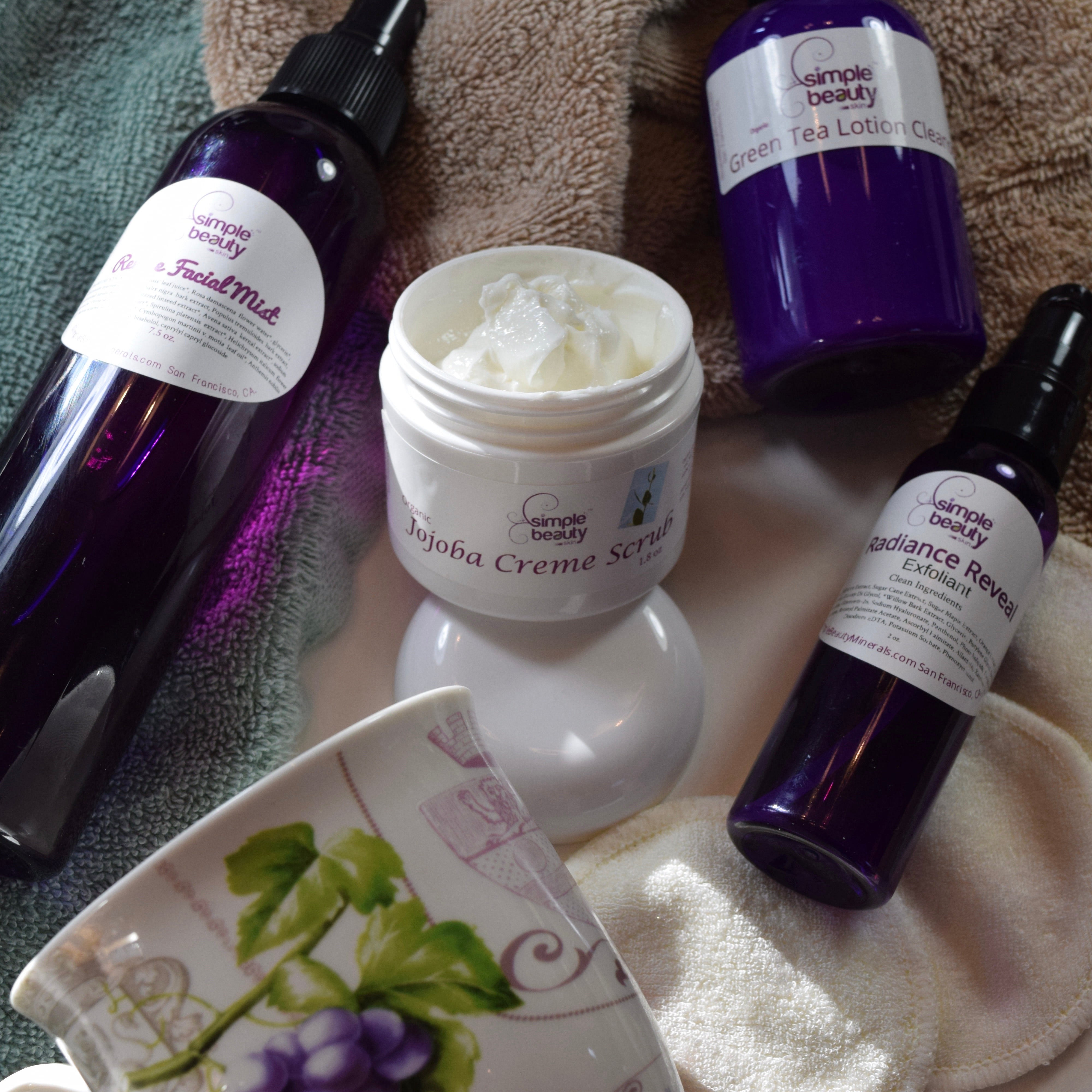 purple bottles of skincare surrounding open jar of scrub