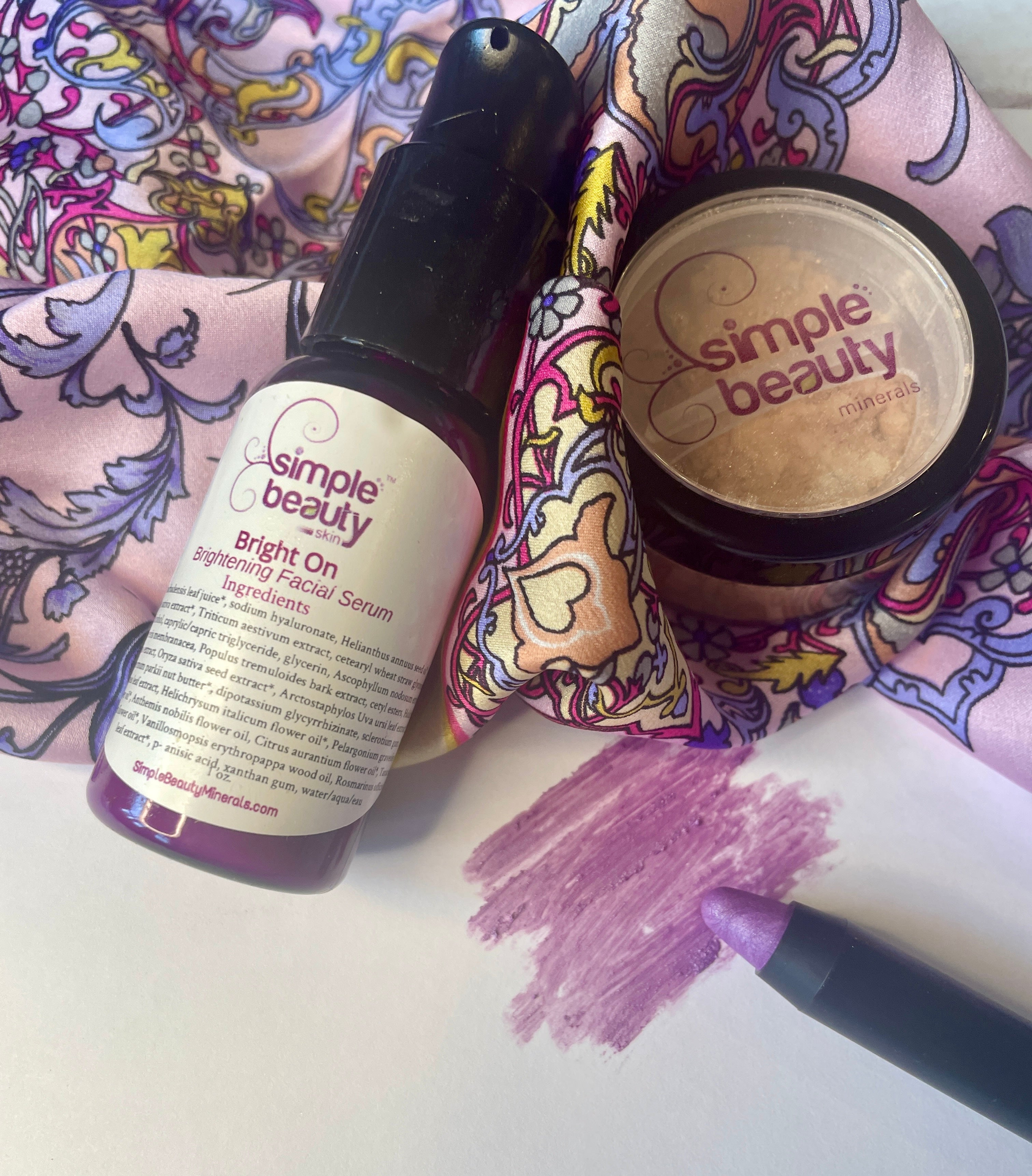 serum, foundation, moondust pencil and swatch with pattern scarf