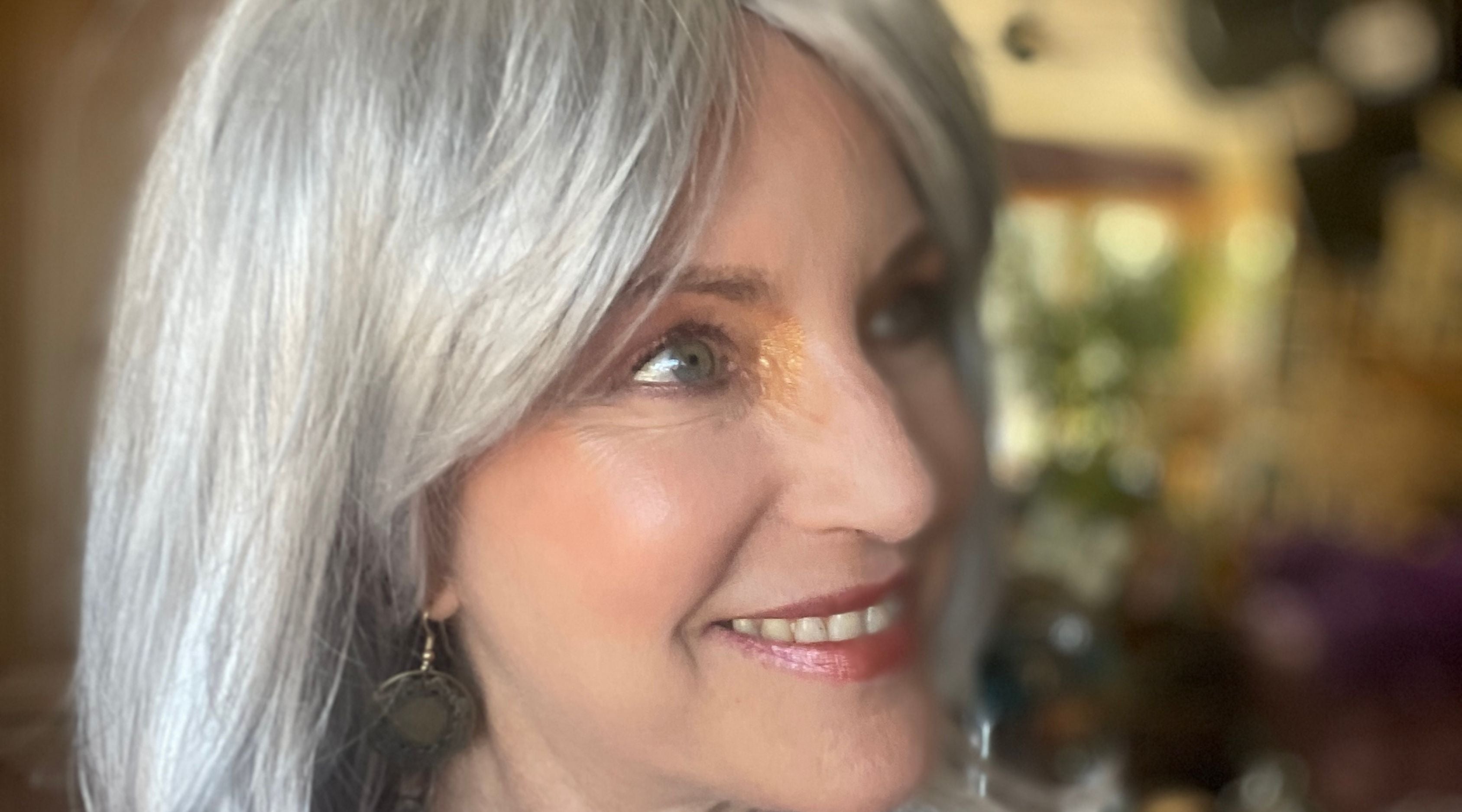 mature woman with silver hair and golden makeup.