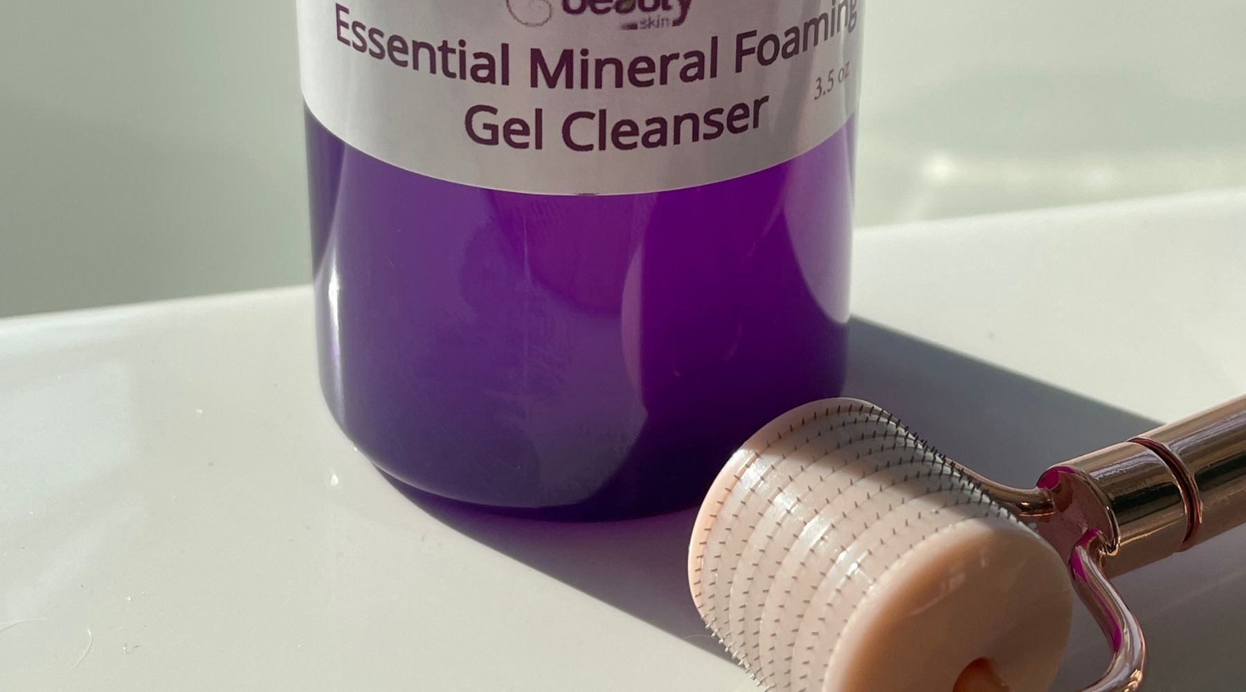 mineral gel cleanser purple bottle with pink dermal roller