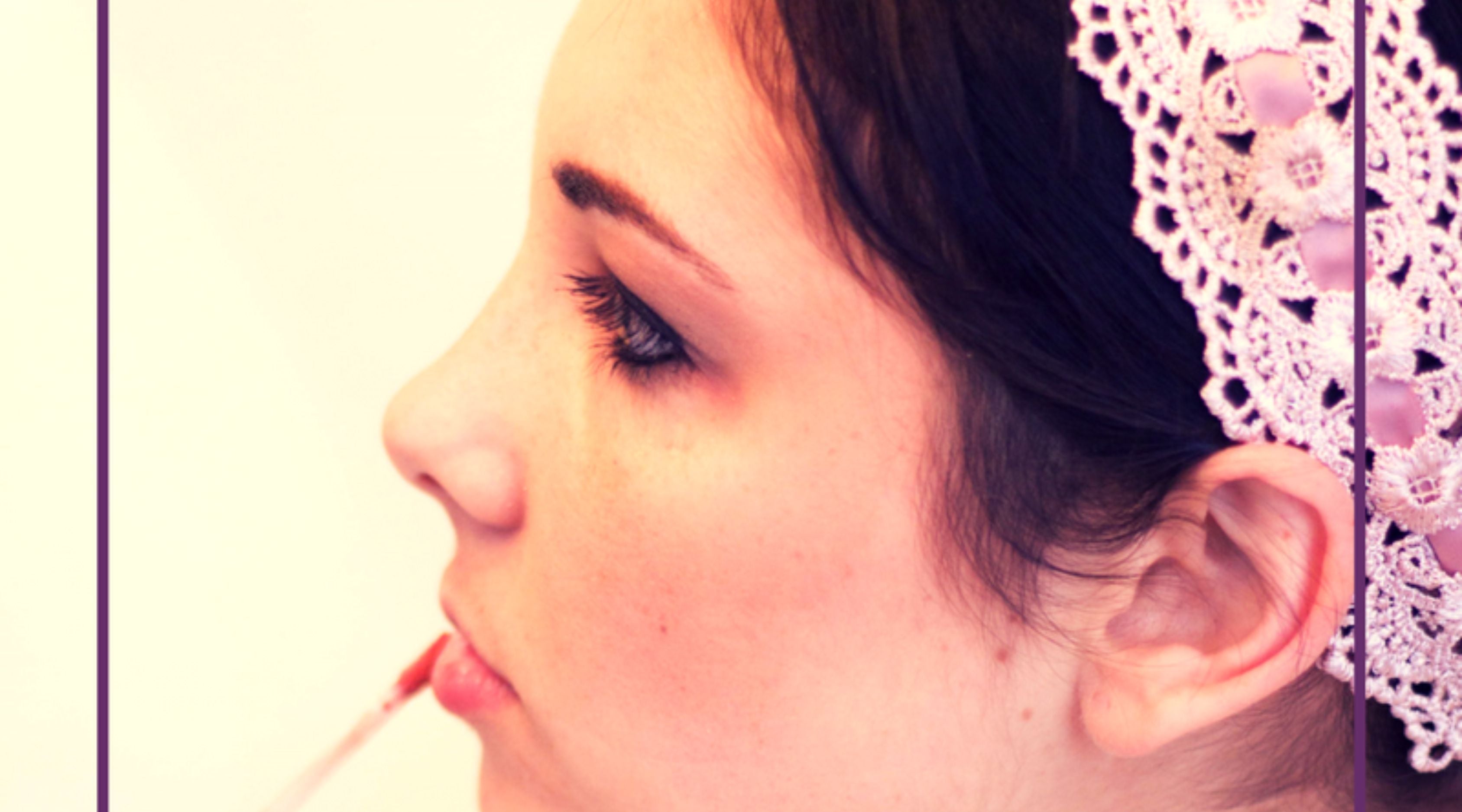 woman applying pink lip gloss with pink headband on.