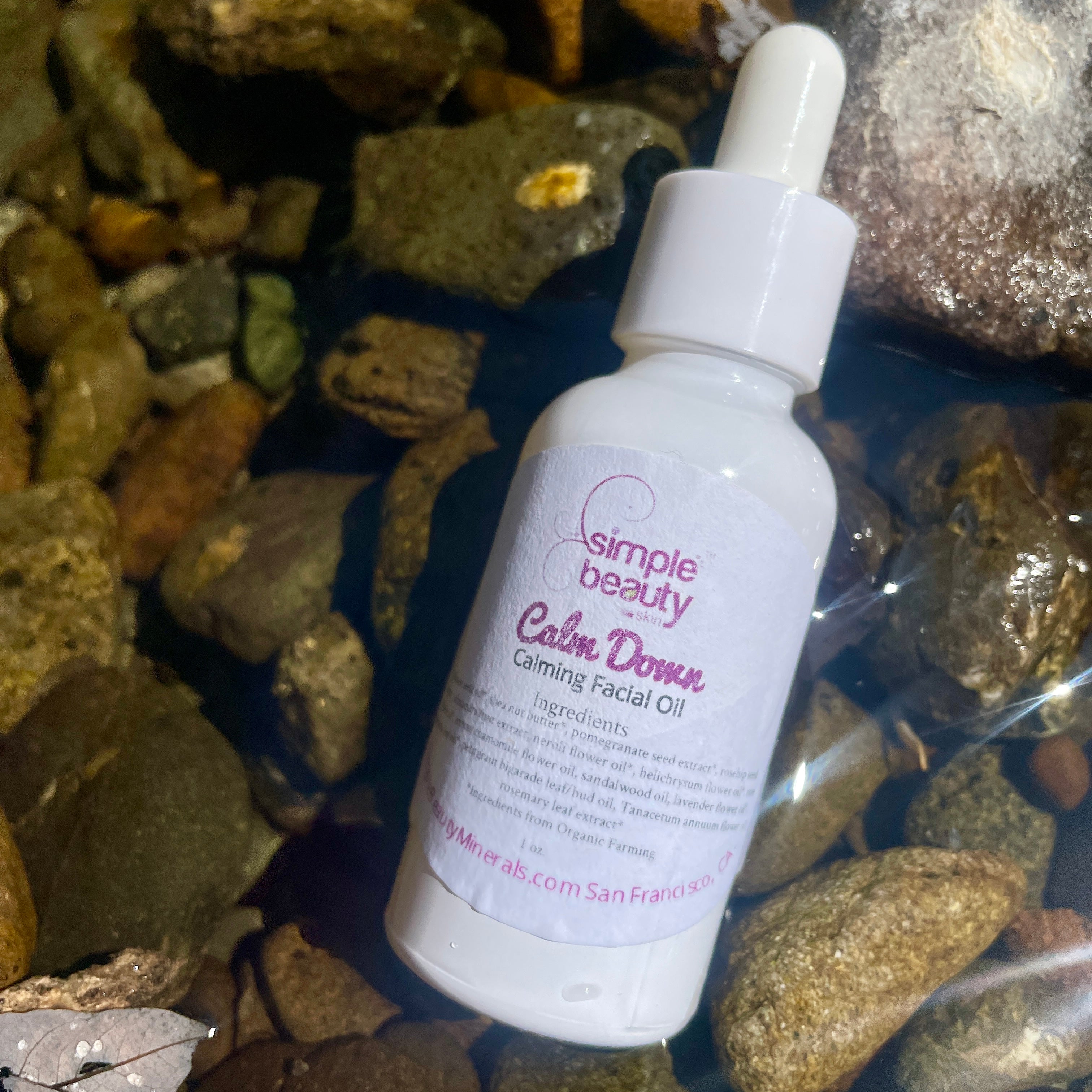 white bottle of facial oil in creek bed.