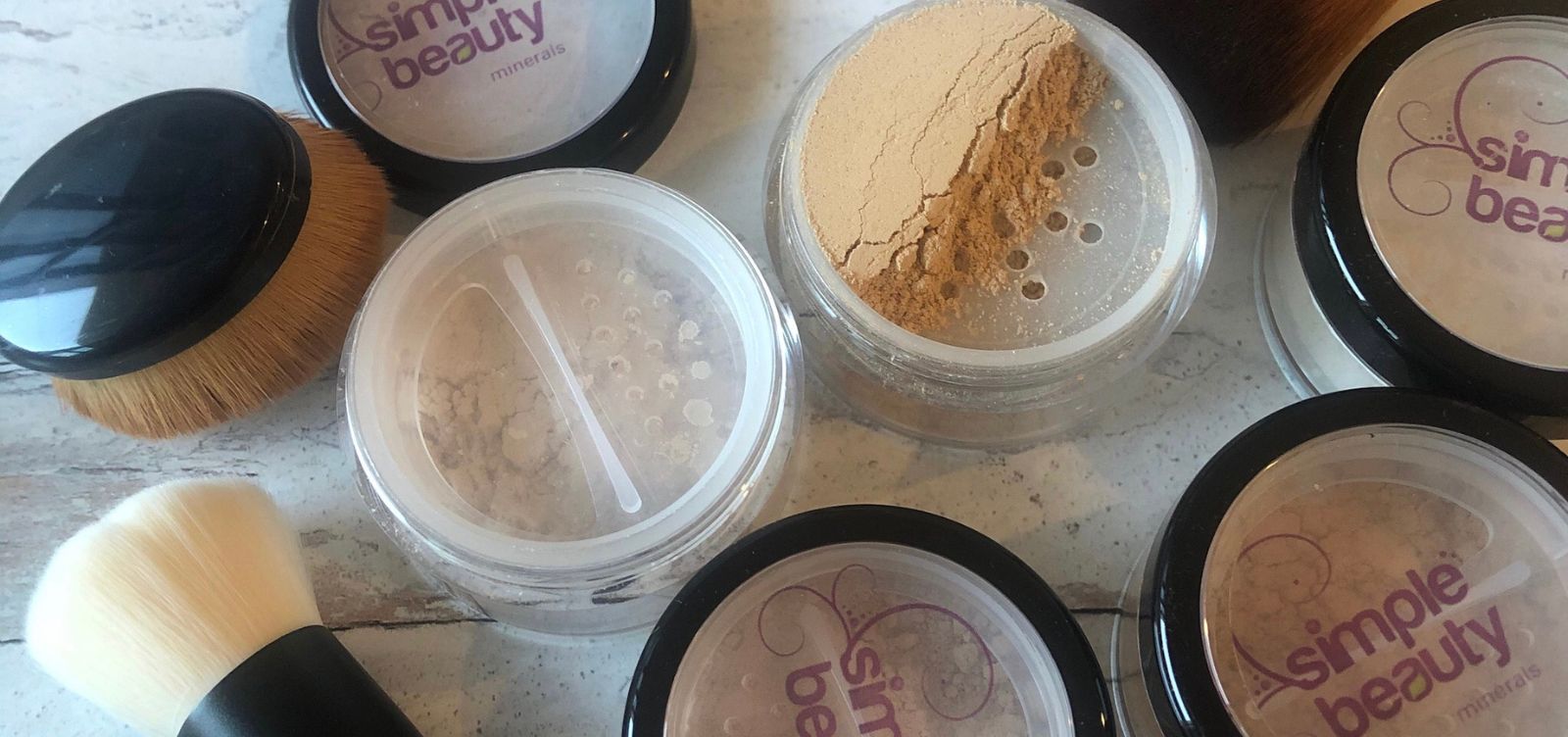 pots of mineral foundation, some open, with makeup brush.