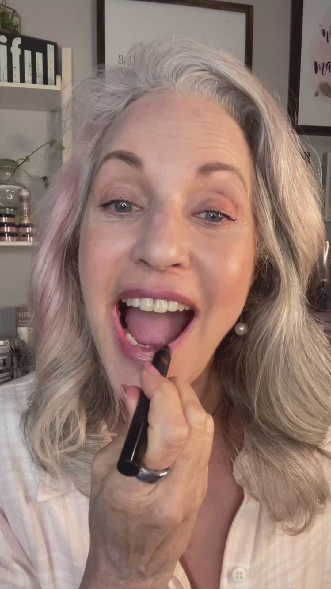 mature woman applying multitasking makeup stick.