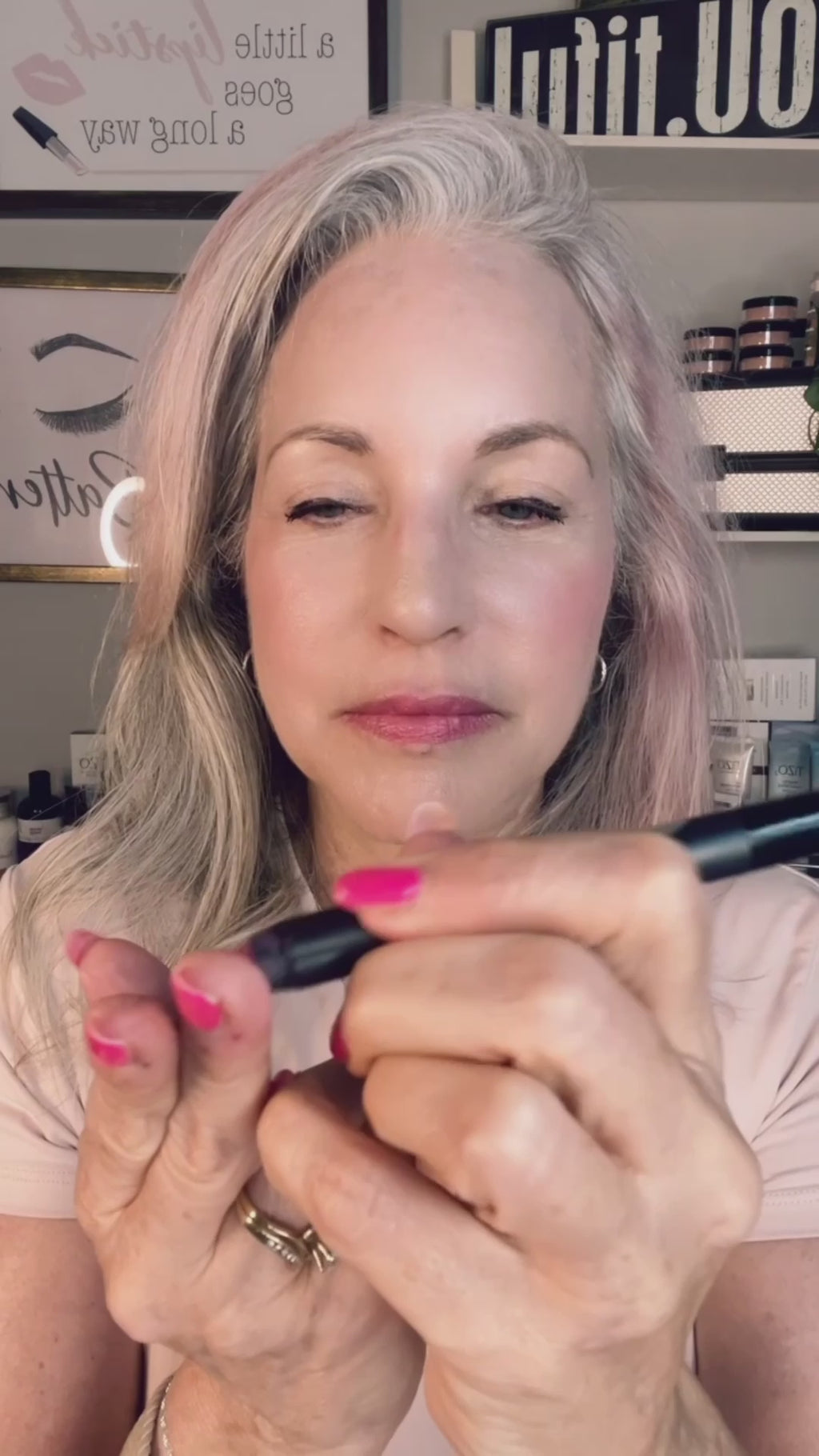 woman applying pink crayon to eyelids.