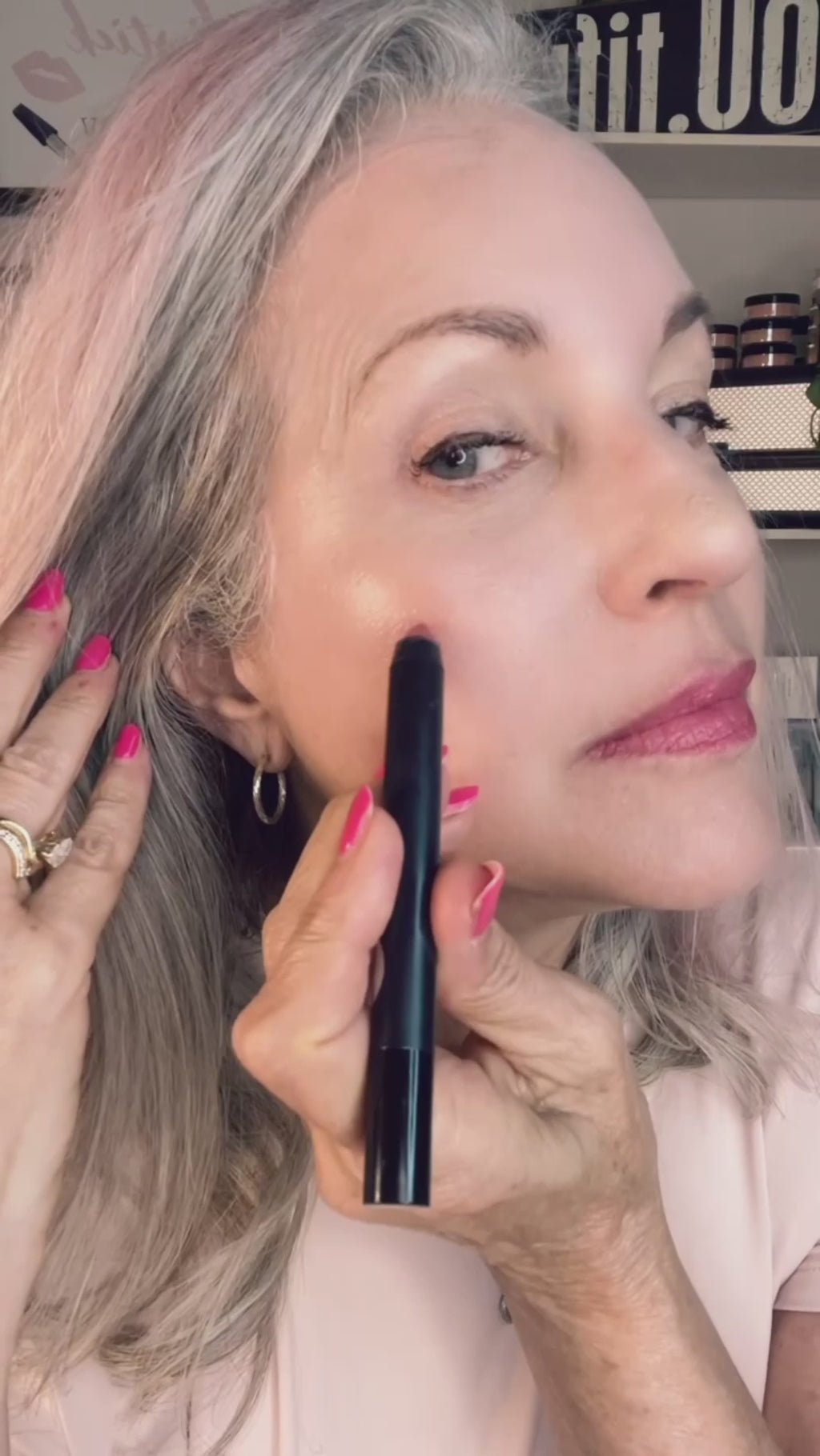 woman applying pink makeup crayon.