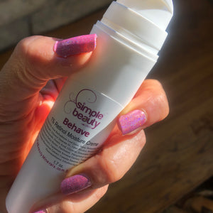 white bottle of moisture creme in woman's hand with pink polish
